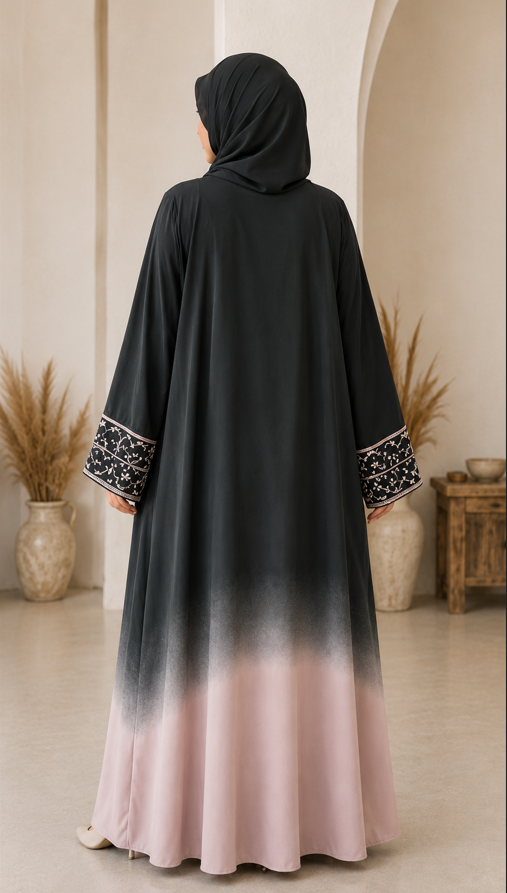 Woman wearing a black and pink gradient abaya with intricate detailing in a decorated room.