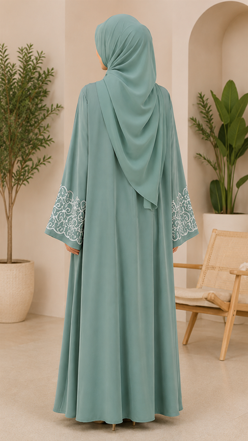 Person wearing a light blue abaya with embroidery in a room with plants and a chair.