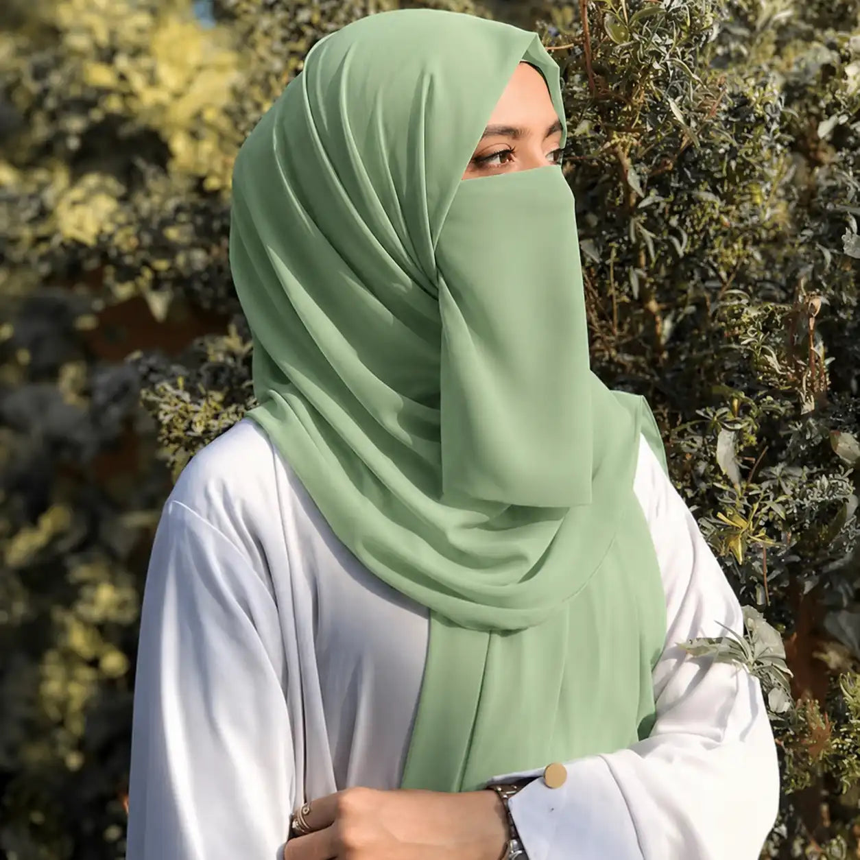 Woman wearing sage green georgette hijab with matching niqab outdoors